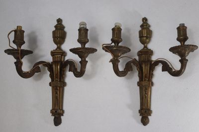 three antique brass wall sconces on a white wall