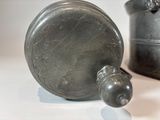 a small metal object sitting on a table next to a cup