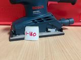 La ponceuse orbitale Bosch est posée sur une table, à côté d'une boîte rouge.