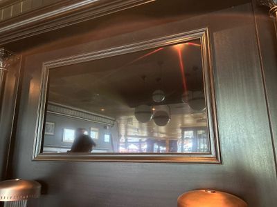 le reflet d'une personne dans un miroir accroché au mur