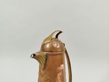 an antique copper coffee pot and a wooden spoon on a white background