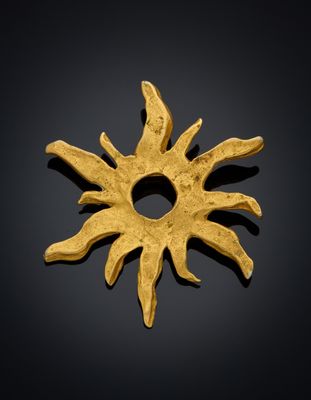 une image représentant un pendentif en forme de soleil doré sur fond noir