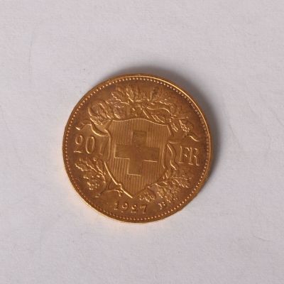 a gold coin on a white surface with a picture of a coat of arms
