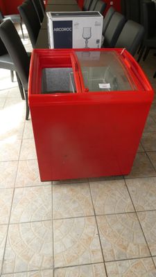 une table rouge avec un plateau en verre et des chaises noires