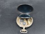 a small silver pocket watch on a black surface