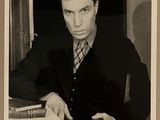 photographie en noir et blanc d'un homme en costume-cravate tenant un livre