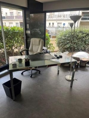 a glass desk with a laptop on it in the corner of a room
