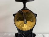 an old black and gold scale sitting on top of a white table