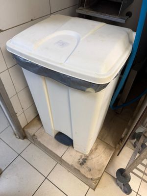 a trash can in the corner of a bathroom