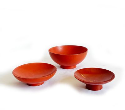 trois bols rouges et un bol posés sur une surface blanche