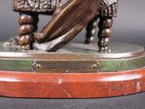 a bronze statue of a man holding a surfboard on a wooden base