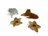 three figurines of animals and flowers on a white surface