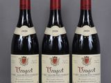 three bottles of red wine sitting on top of a glass table