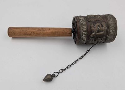 une vieille cloche en métal munie d'une poignée en bois et d'une chaîne qui l'entoure