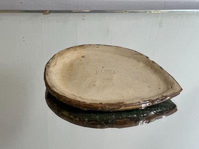 a small piece of pottery sitting on top of a glass table