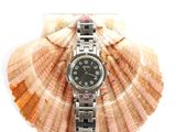 a watch sitting on top of a shell on a white surface