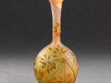 un vase en verre orange posé sur une table près d'un mur gris