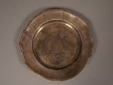 une assiette en argent accrochée au mur sur un fond blanc