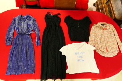 beaucoup de vêtements posés sur une table recouverte d'une nappe rouge