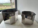 two metal containers sitting on a table next to a window