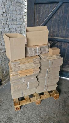 une pile de cartons posée sur une palette devant la porte d'un garage