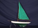 un petit voilier avec une voile verte posé sur une table