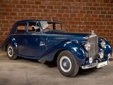 a blue car that is parked in front of a brick wall
