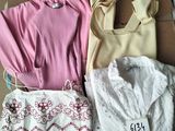 Trois vêtements pour femmes sont posés sur un carton posé par terre.