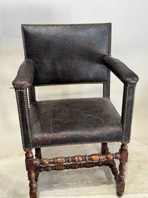 un vieux fauteuil en cuir avec des pieds en bois et une assise en cuir