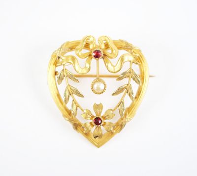a gold heart shaped brooch with a red stone surrounded by leaves
