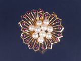 une image représentant une broche en or ornée de perles et de grenats