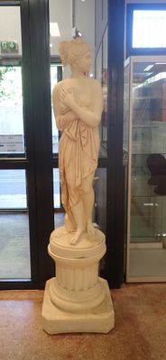 a statue of a woman standing on a pedestal in front of a glass door