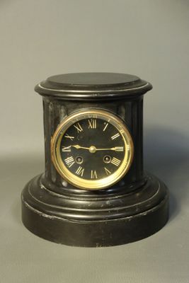 a small black clock with roman numerals on it