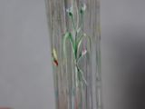 a hand holding a glass vase with flowers painted on it
