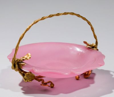 un bol rose avec une anse dorée sur un fond blanc