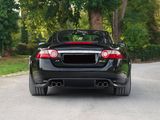 the rear end of a black sports car parked on the side of a road