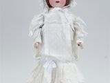 an antique porcelain doll of a woman in a white dress and bonnet