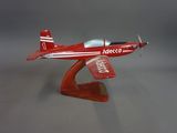 une petite maquette d'avion rouge posée sur un socle en bois