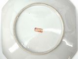 a white plate with a brown border and a red tag on it