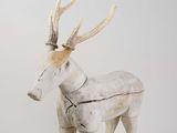 sculpture of a white deer with antlers on it ' s head standing on a white surface