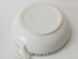 a white bowl with a bird on it sitting on a table