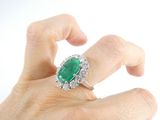 a woman ' s hand holding a ring with a green stone