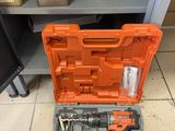 une boîte à outils orange posée sur un sol carrelé, à côté d'une étagère