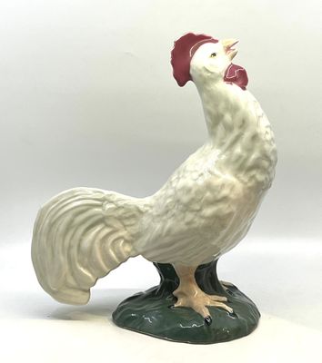 une figurine représentant un coq blanc sur un socle vert