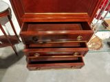 a wooden cabinet with three drawers and a glass top