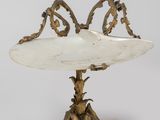 une plaque ancienne en laiton ornée d'un oiseau, posée sur un socle