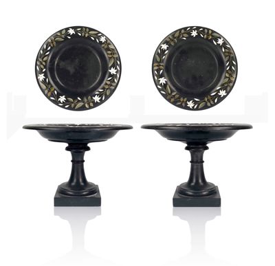pair of black and gold plates on pedestals on white background