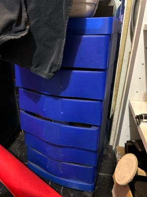 une commode bleue dans une pièce où se trouve une chaise rouge