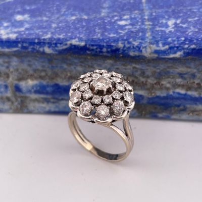 a close up of a diamond cluster ring on a blue stone