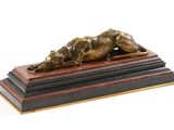 sculpture en bronze représentant un chien couché sur un socle en bois, sur fond blanc